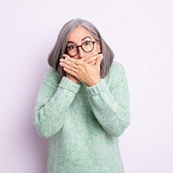 a woman covering her mouth to hide her teeth