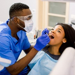 Dentist using tools to check patient's teeth and gums