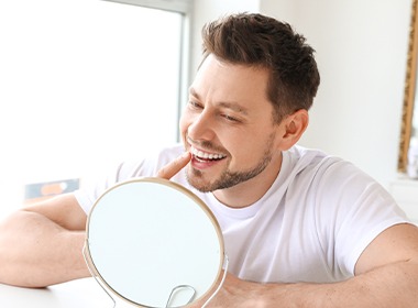 Man pointing to smile and looking in a mirror