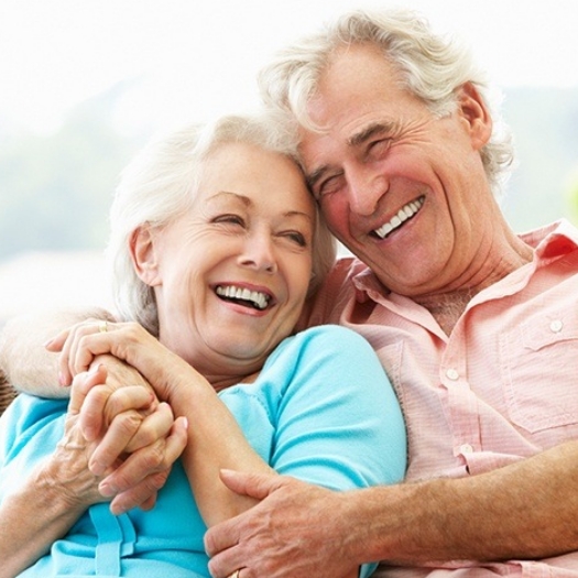 Man and woman smiling after full mouth rehabilitation