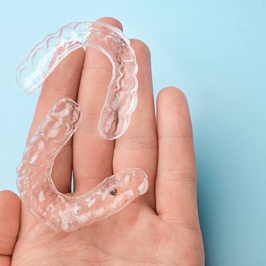 a person holding a set of clear aligners
