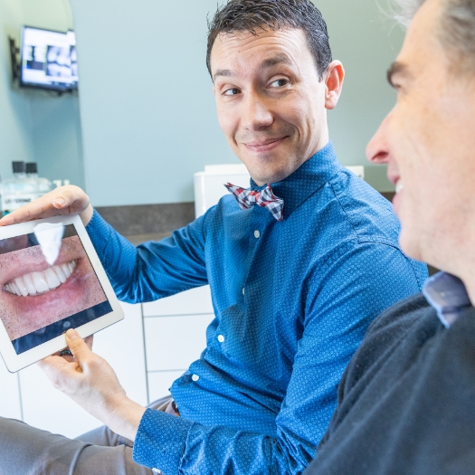 Woman looking at virtual smile design on tablet computer