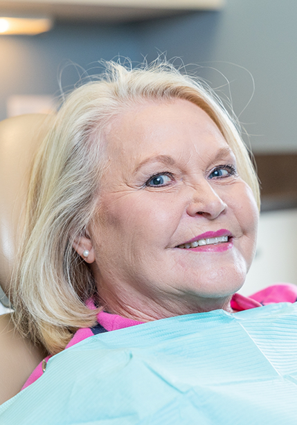 Woman in the dental chair smiling with dentures in Summerfield