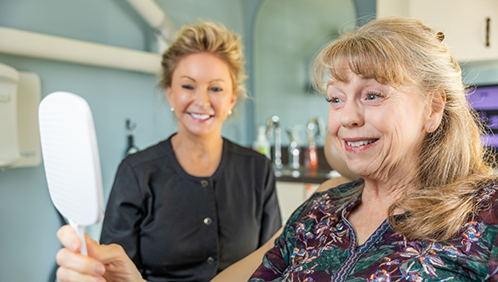Dental patient admiring her smile in a mirror
