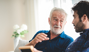 Man talking to man next to him on a couch