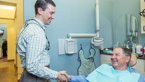 Doctor Parry shaking hands with a dental patient