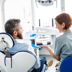 Female dentist smiling at patient while showing them X-ray