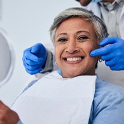 Woman smiling while holding handheld mirror