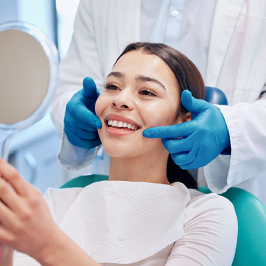Patient smiling at reflection in handheld mirror