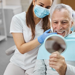 An older man admiring his new dental implant