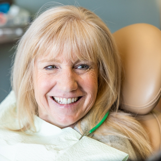 Woman sharing flawless smile after dental implant tooth replacement