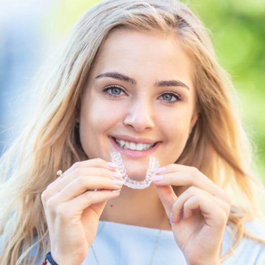 woman holding Invisalign clear aligner 