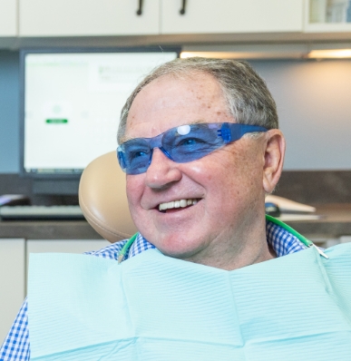 man smiling while holding dental mirror