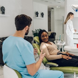 Smiling patient relaxing in dental chair while talking to dentist