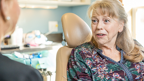Woman in the treatment chair talking to her dentist