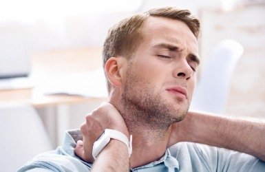Man in need of T M J therapy holding neck in pain