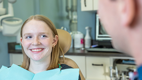 Young woman in the dental chair smiling at her dentist