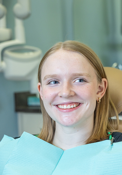 Teenage girl in the dental chair smiling at her dentist