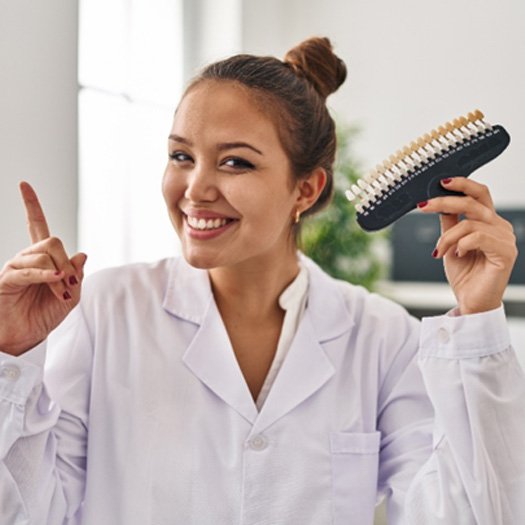 A young dentist holding teeth whitening samples while surprised with an idea