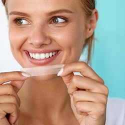 A woman using a teeth whitening strip