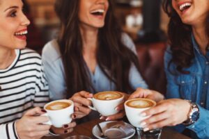 Three friends laughing and having coffee together.